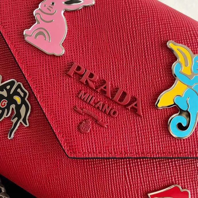 pra*a red monoCh*0me flap bag with metal appliques