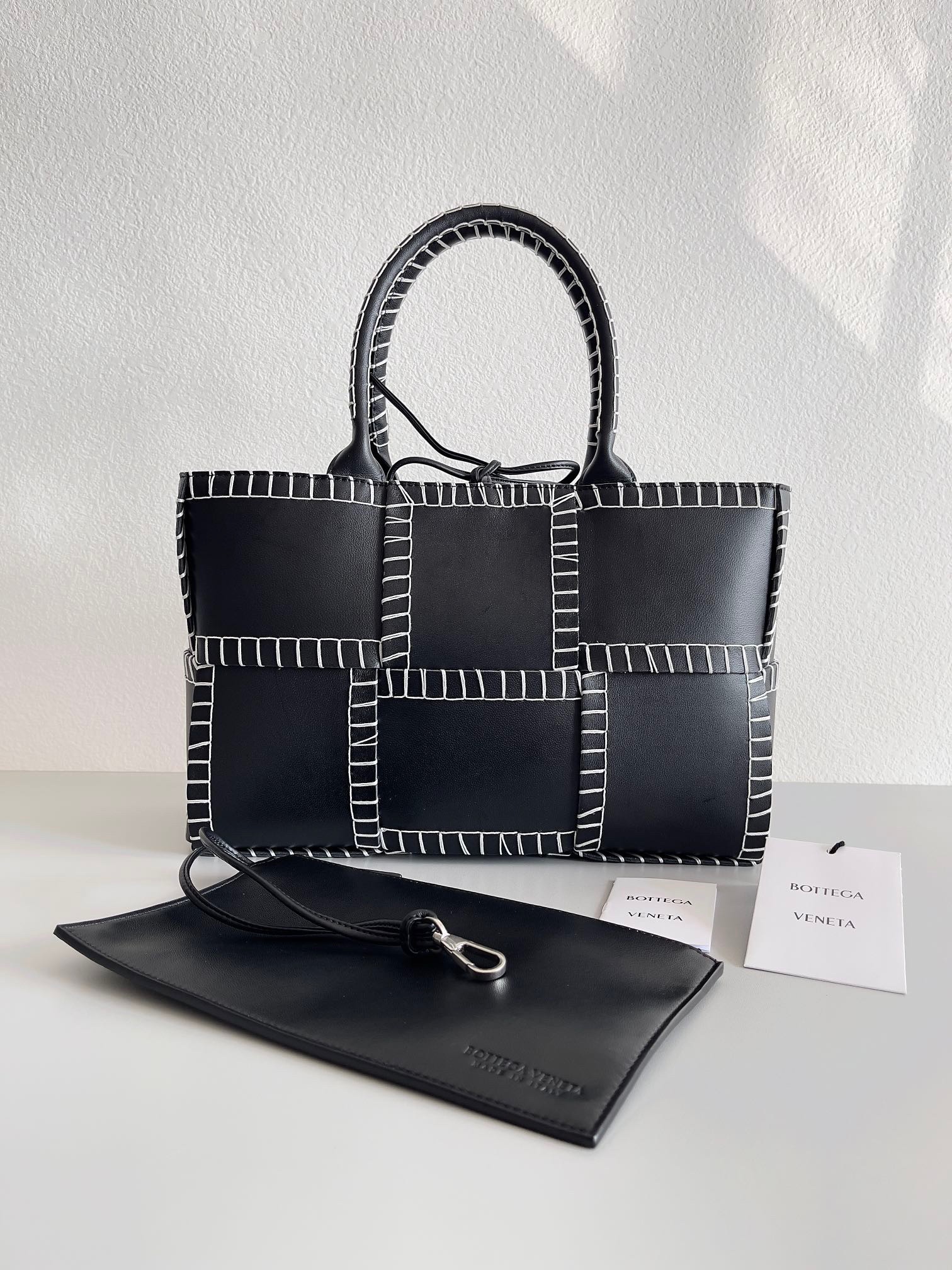 bo*te*ga Ve*ne*ta black arco small tote with white overlock stitching